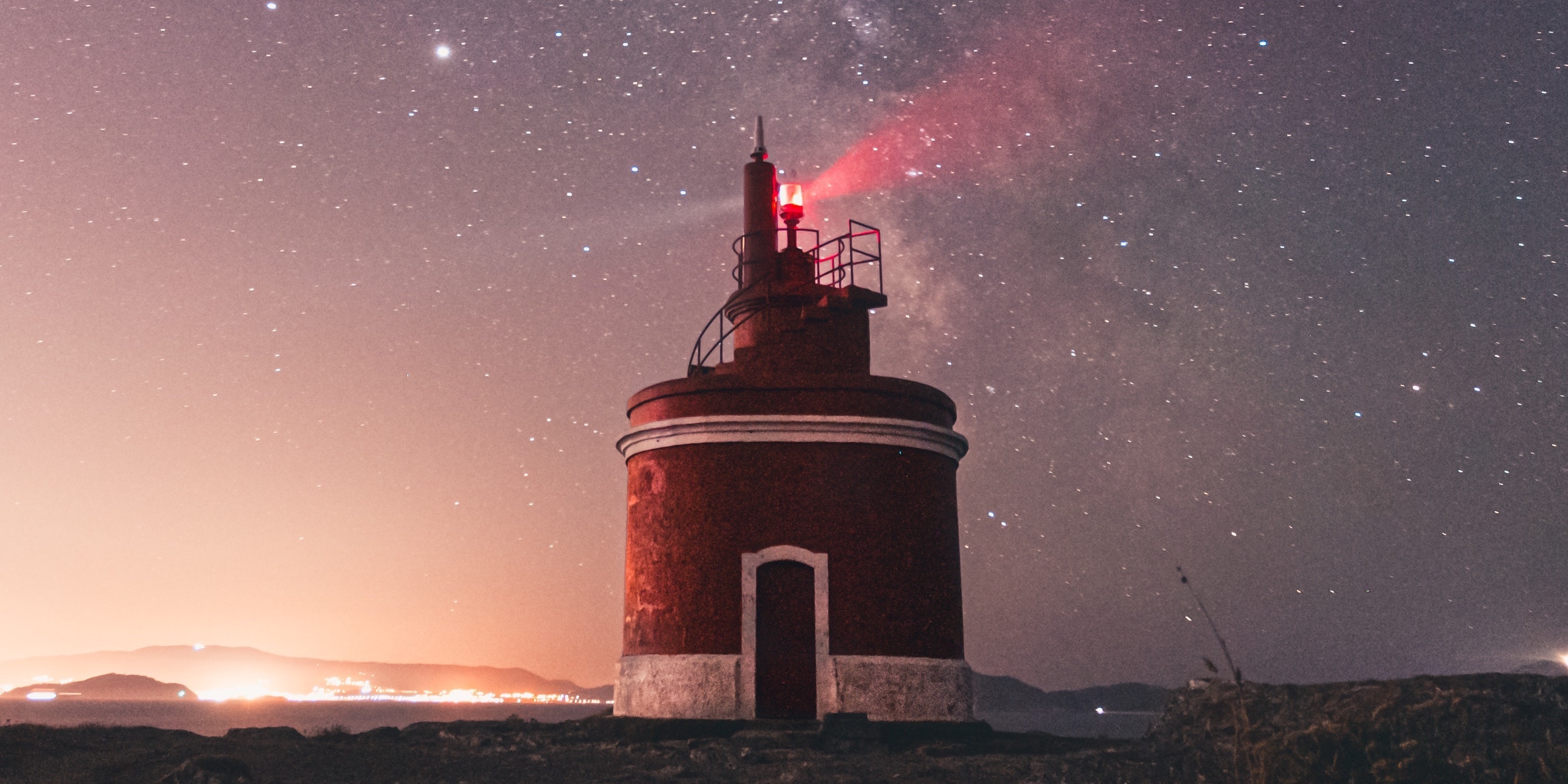 Lighthouse with visible light beam under the milky way galaxy